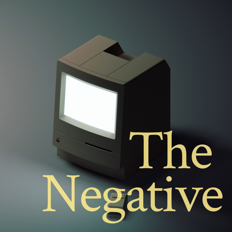 A vintage Macintosh computer on a dark slate background, with The Negative in amber serif type on its screen
